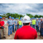 Crossland Mentor leading a meeting with a group of apprentices wearing PPE outside on a job site.