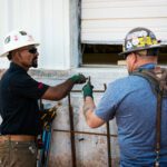 Two construction workers working on a building.